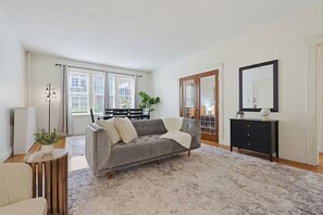 Una sala de estar moderna con un sofá gris, un mueble negro y un espejo grande en la pared.