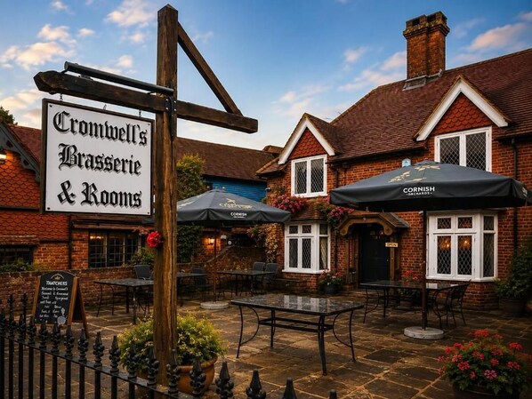 Een traditionele pub met terras, een bord met Cromwell's Brasserie & Rooms erop, en een bord van Cornish Orchard.