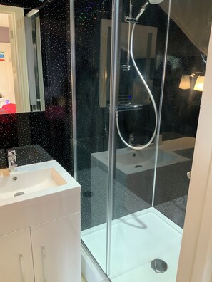 A modern bathroom with a glass shower enclosure, a white sink, and a mirror. - The Cromwell Brasserie and rooms Ltd (Cranleigh)