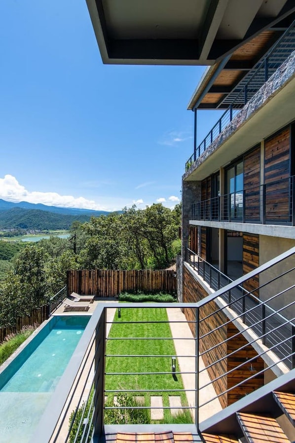 A modern building with a pool, a grassy area, and a view of mountains. - Exclusiva Casa en El Santuario, Vista al Lago (Valle de Bravo)