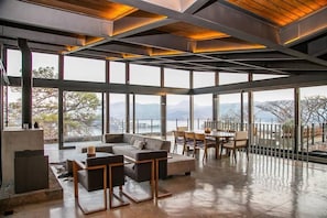 A spacious interior with a large seating area, a dining table, and a view of the outdoors. - Exclusiva Casa en El Santuario, Vista al Lago (Valle de Bravo)