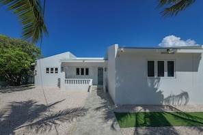 A two-story white building with a covered porch and a small front yard. - Luxury 4BR Villa • Pool • Walk to Palm Beach (Noord)