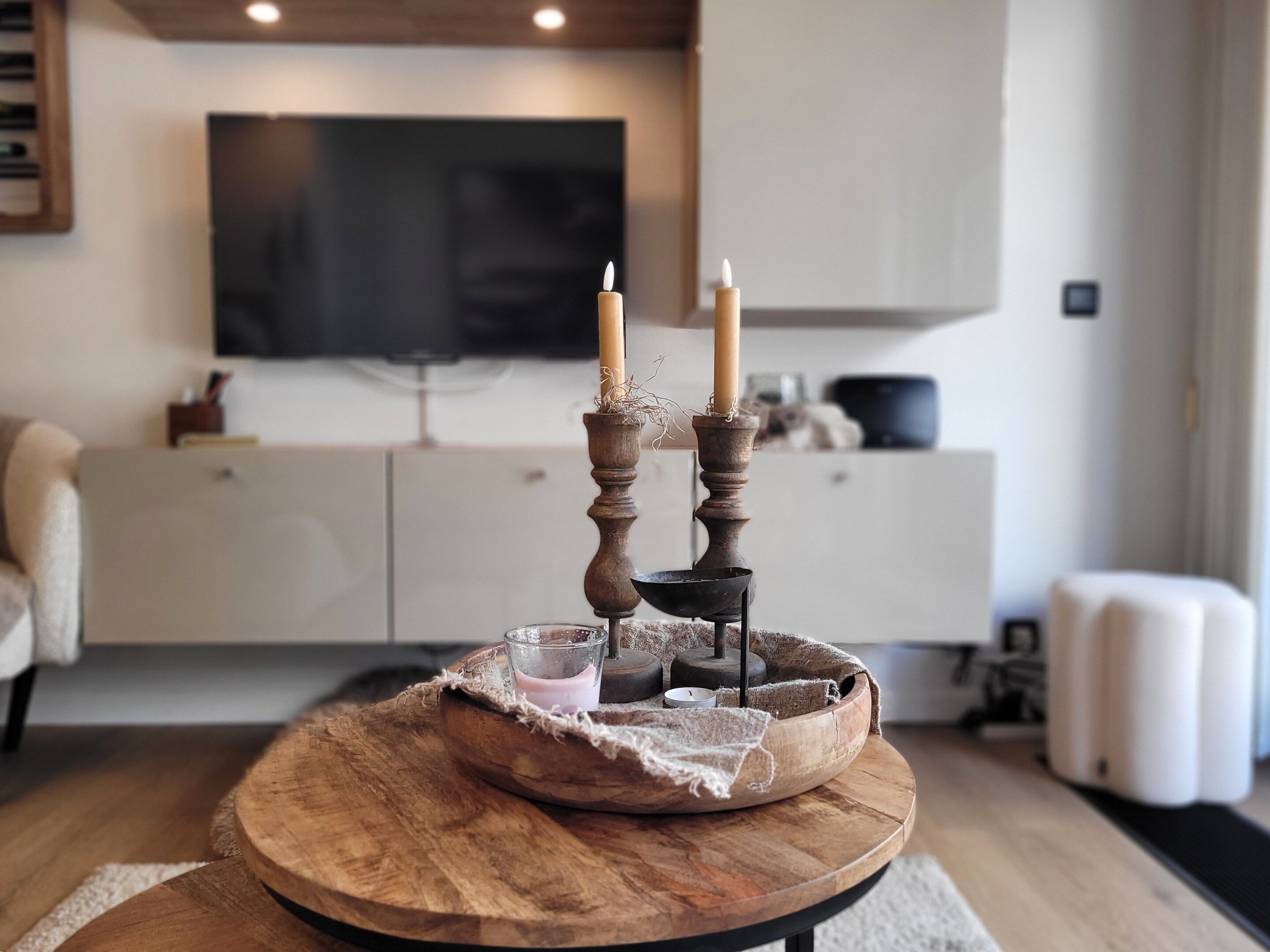Un salon moderne avec une table basse en bois, deux bougies et un porte-bougie en verre.