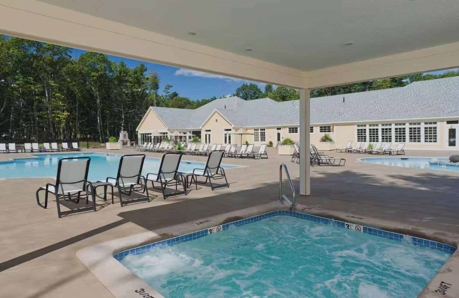 A pool area with lounge chairs and a hot tub.