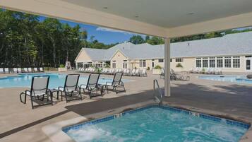A pool area with lounge chairs and a hot tub.