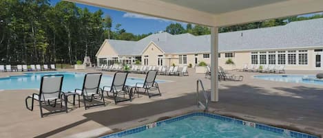 A pool area with lounge chairs and a hot tub.