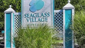 Une enseigne pour le village de Seaglass, avec un logo, le tout entouré de verdure.