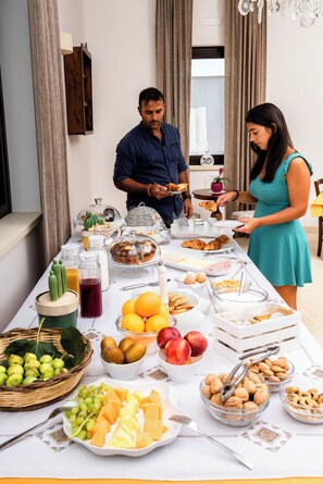 Mesa de buffet com diversos alimentos e uma pessoa servindo.