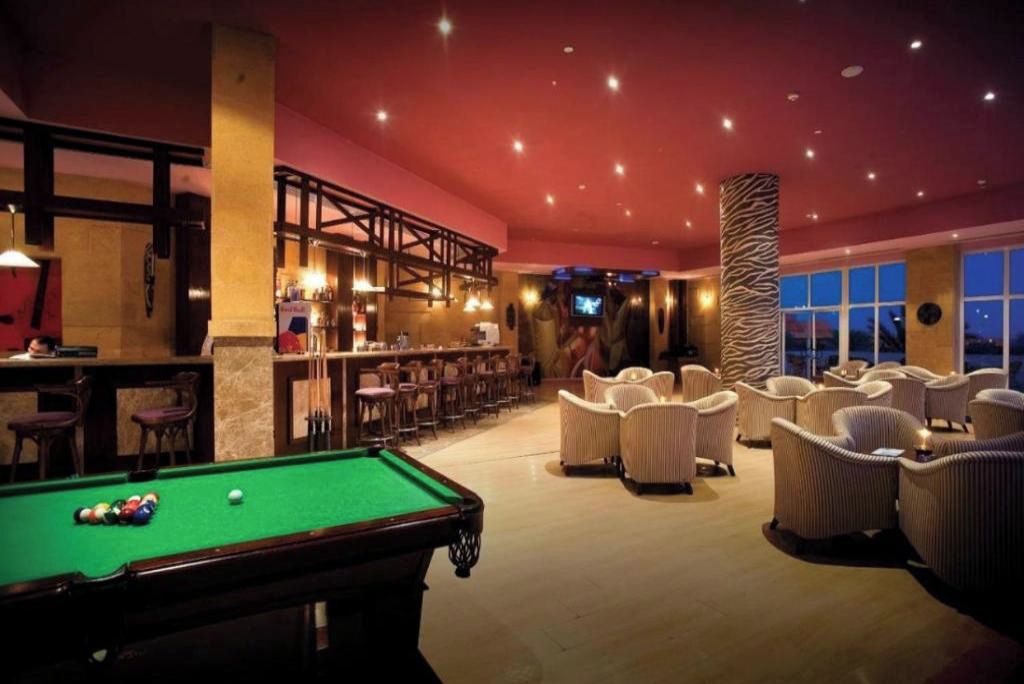 Een pooltafel in een lounge met een bar en zitplaatsen.