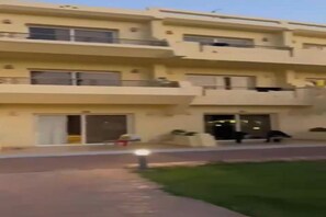 A multi-story residential building with balconies, a gated entrance, and a well-maintained lawn.