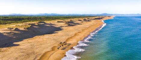 A beach with a clear view of the ocean, a sandy path, and footprints leading to the water.