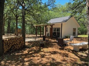 Eine Hütte mit überdachter Terrasse, Sitzgelegenheiten im Freien und einer Steinwand.