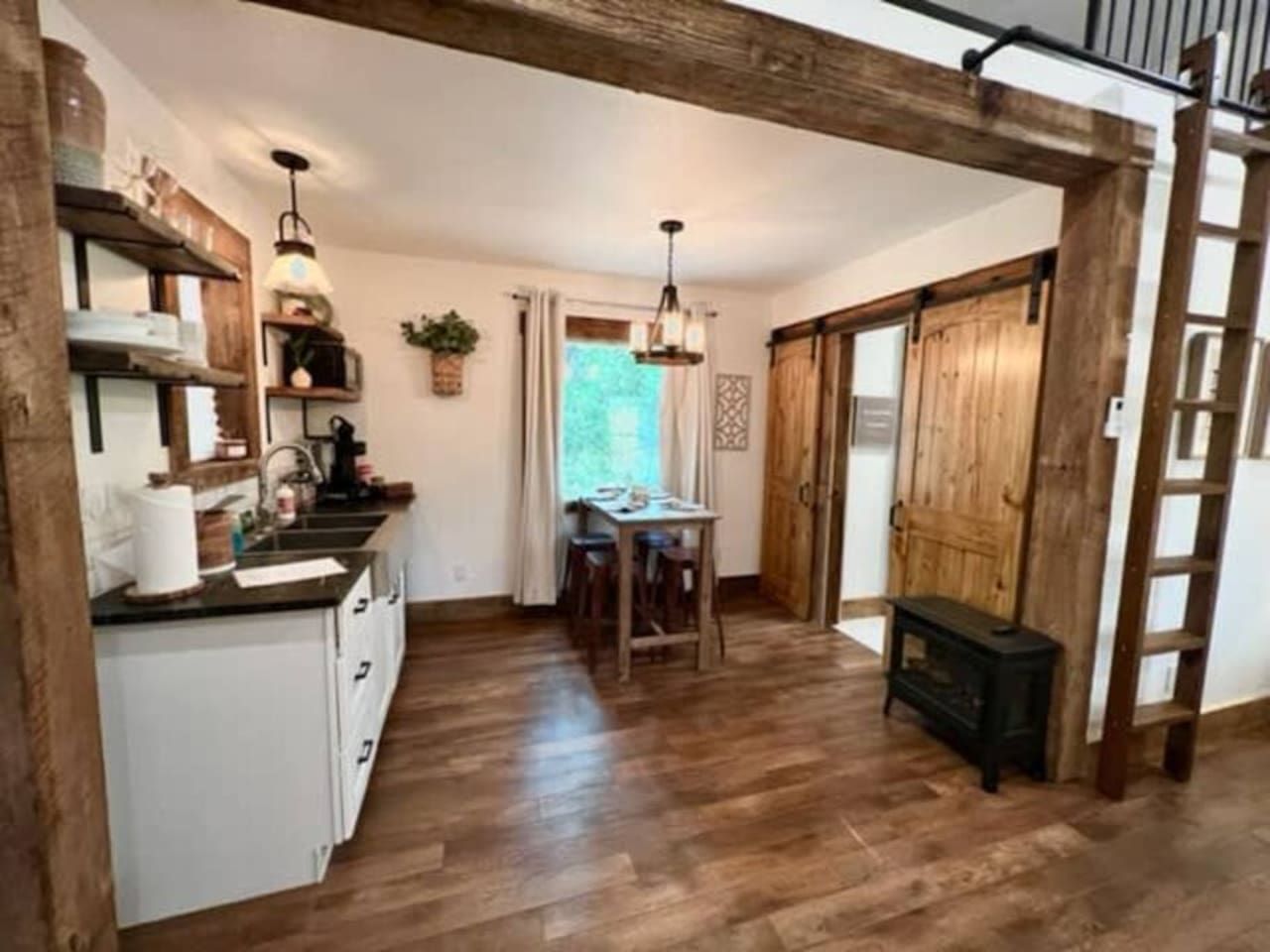 A kitchen with a wooden floor, a dining table, and a black cabinet.