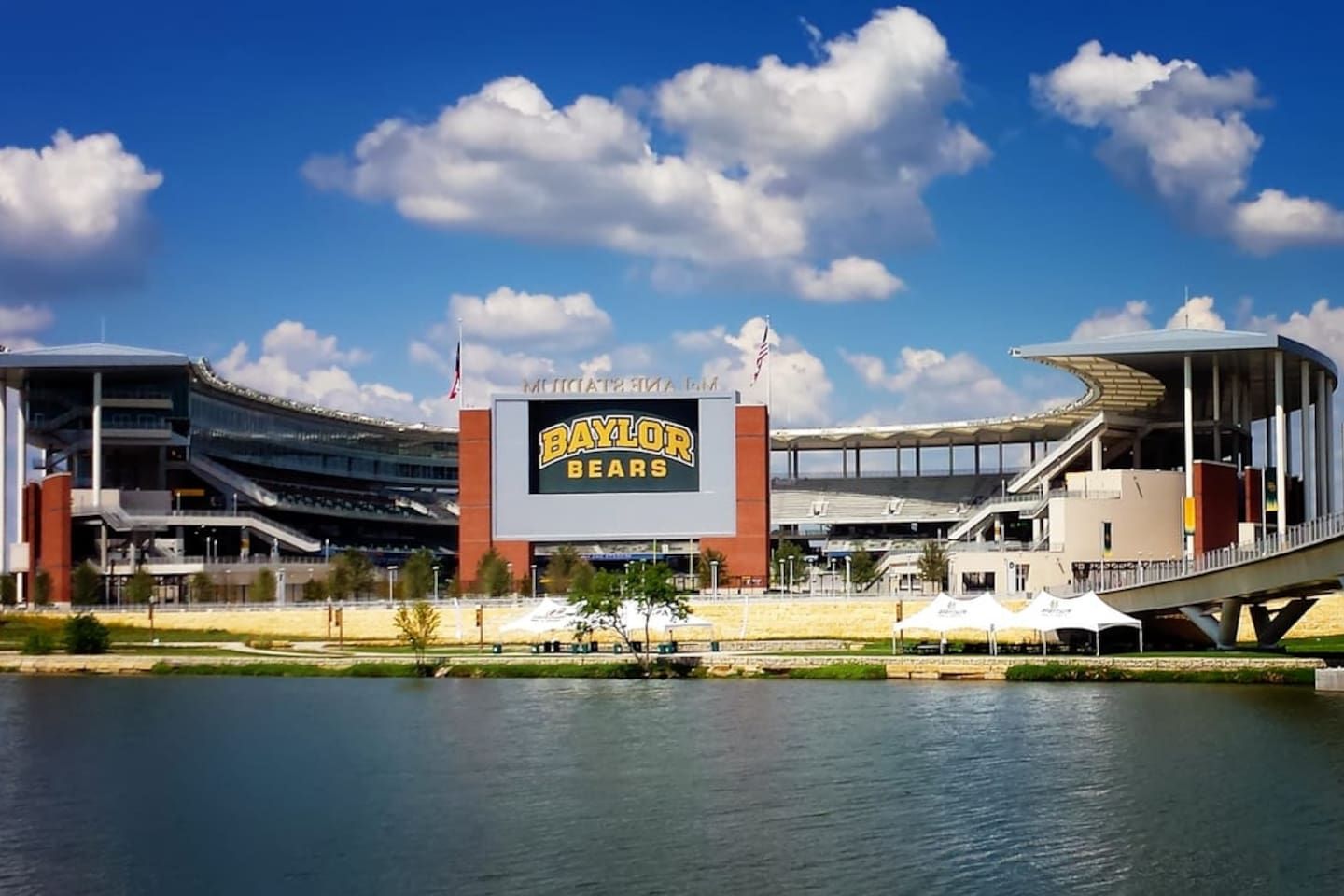 A stadium with a large sign reading 'BAYLOR BEARS' and a flagpole with an American flag.
