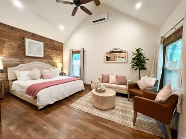 Une chambre avec un grand lit, un canapé, une table basse et un ventilateur de plafond.