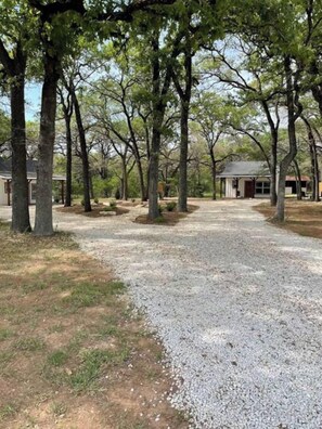 A gravel driveway leading to a building surrounded by trees. - Plush Cabin 4 min to Homestead Heritage 18 min to (Waco)