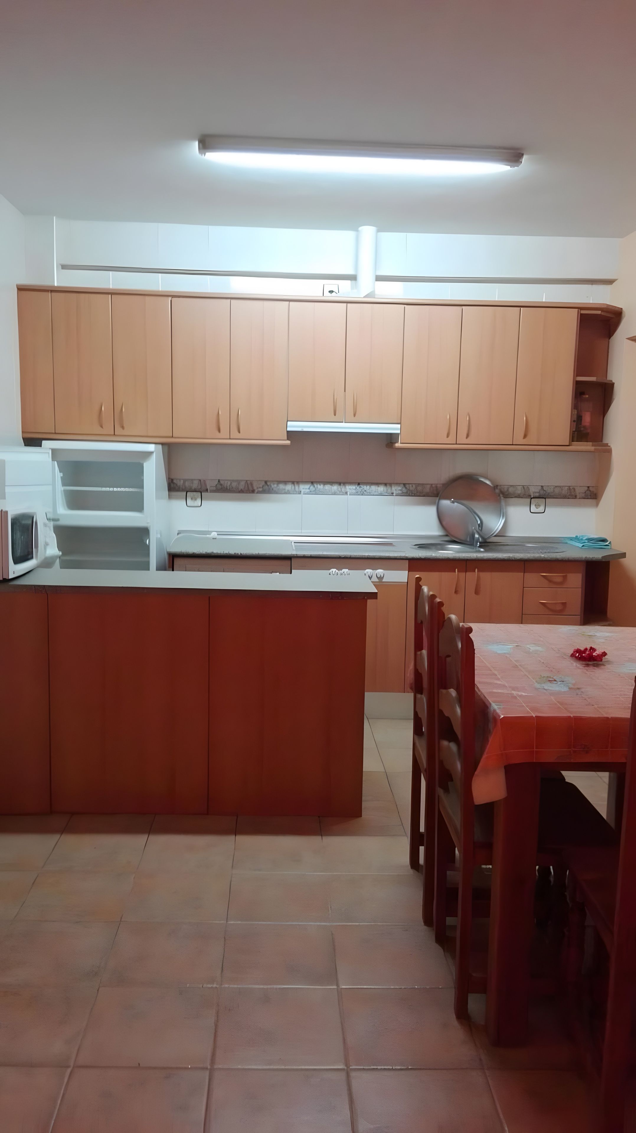 Une cuisine compacte dotée de meubles en bois, d’un four à micro-ondes, d’un évier et d’un coin repas avec une table et des chaises.