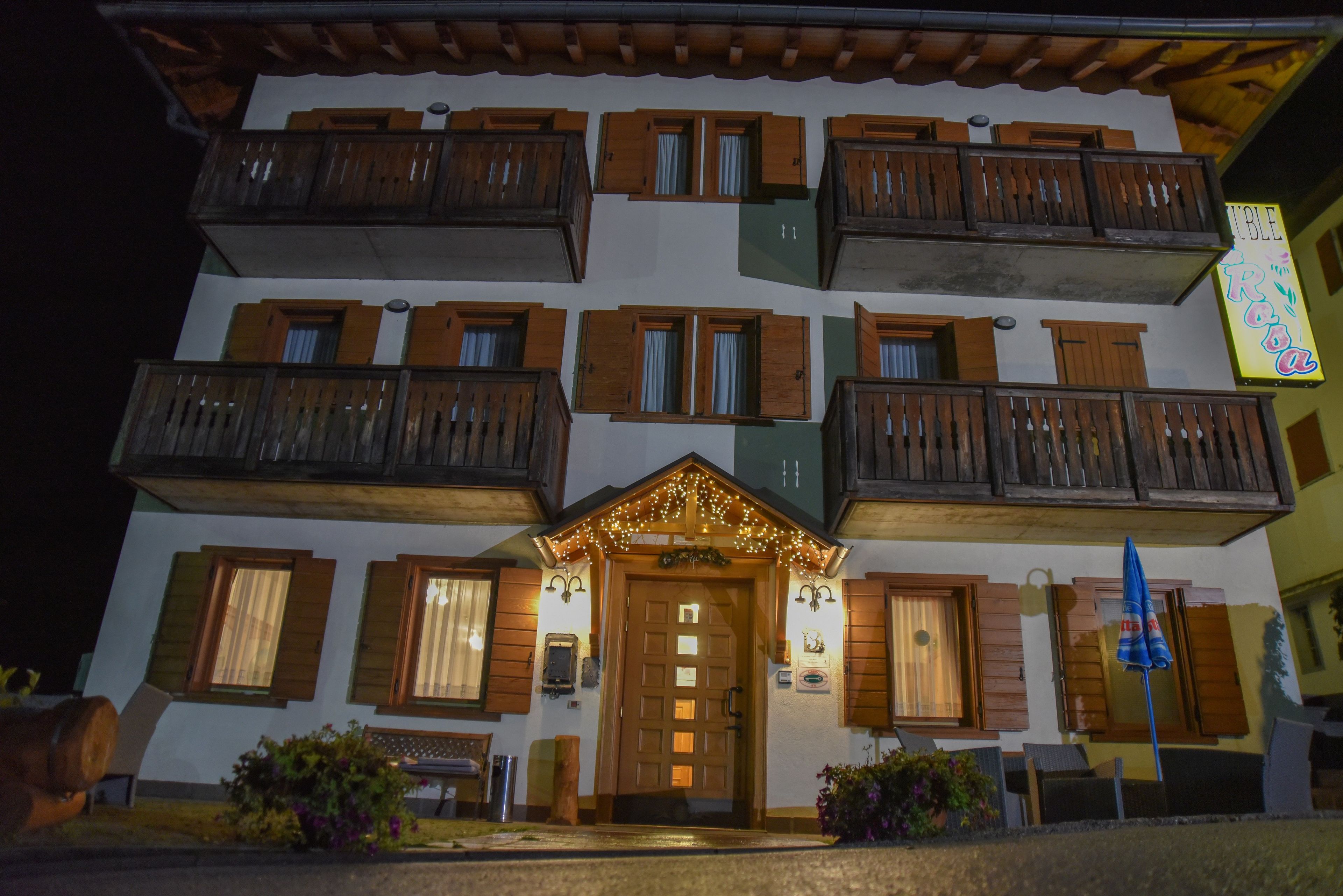 A multi-story building with balconies, a central entrance with a door, and a sign above the entrance.