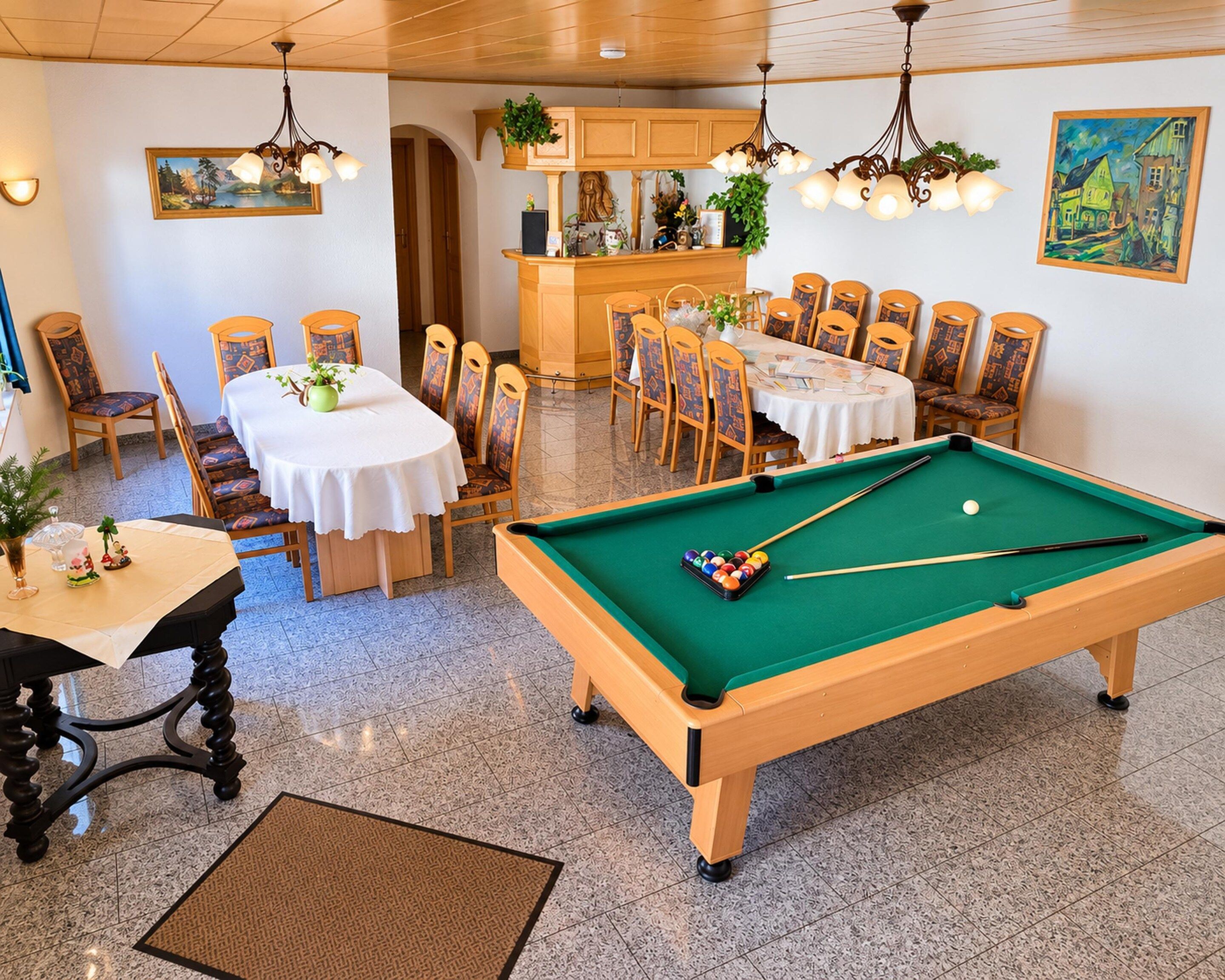 A pool table with a green felt surface, surrounded by wooden chairs with patterned cushions.