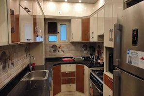 A compact kitchen with a stainless steel refrigerator, a sink, and a stove.