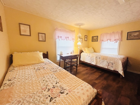 A room with two single beds, a desk, and a chair.