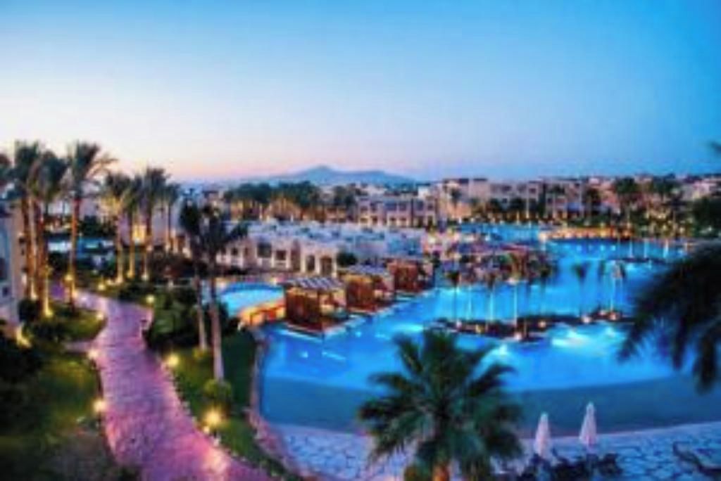 Un resort con diverse piscine, palme e un percorso che conduce alle piscine.