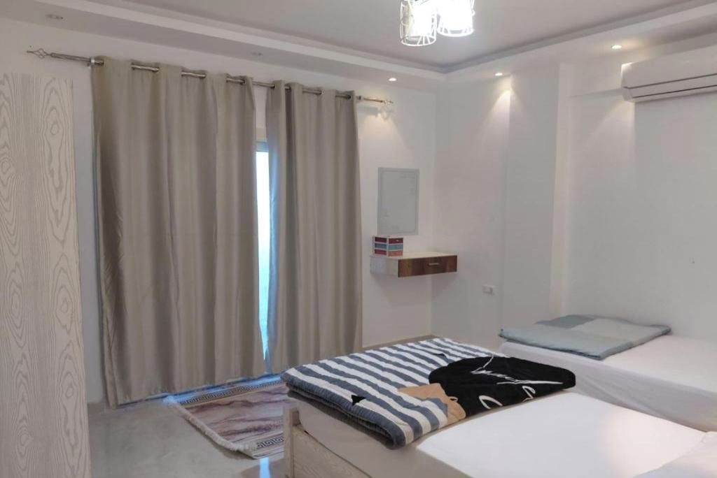 Makuuhuone, jossa on sänky, yöpöytä, riippuvalaisin, ikkuna verhoilla ja seinälle asennettu ilmastointilaite.