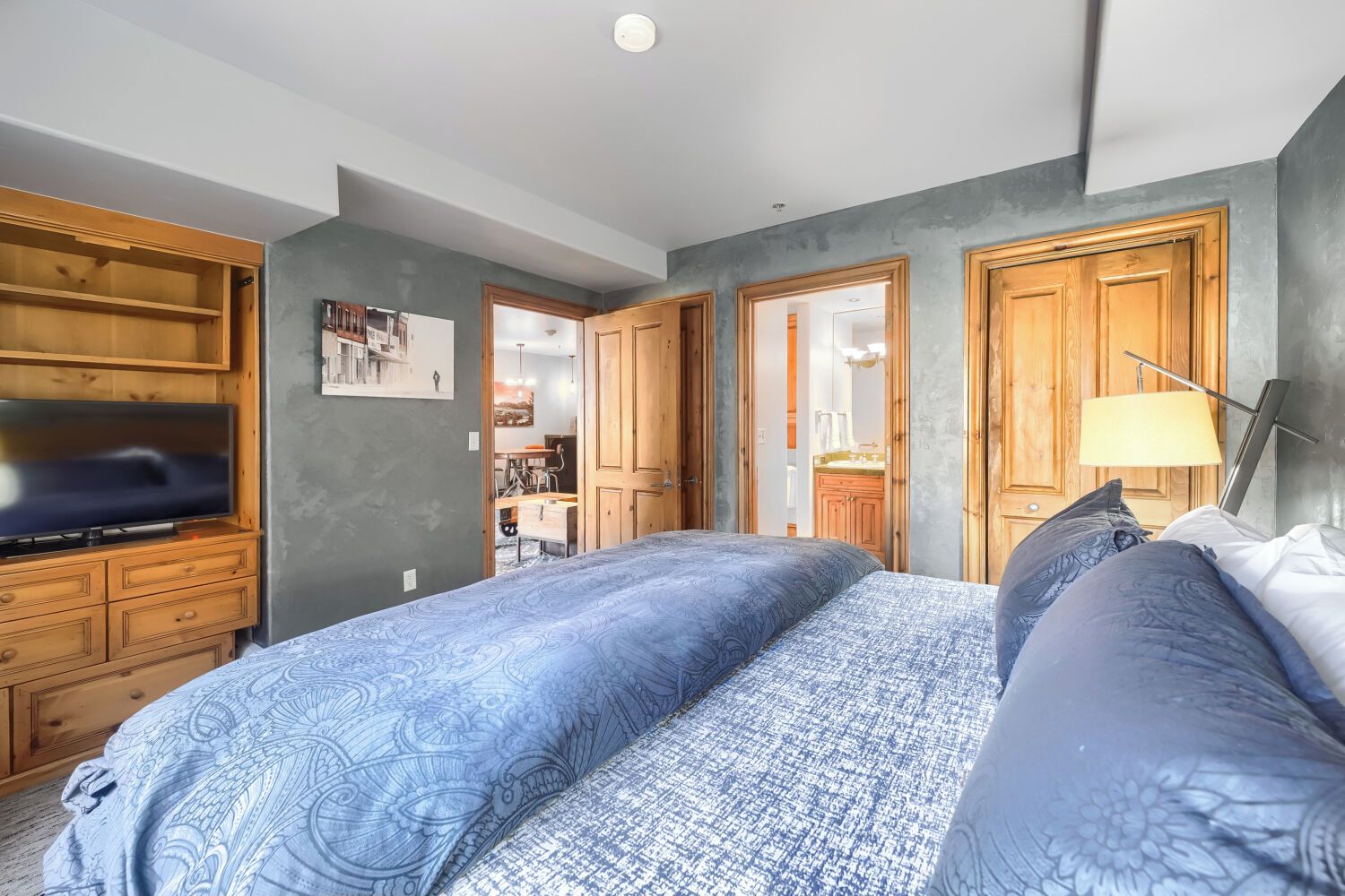 Une chambre à coucher avec un lit, une armoire en bois et un téléviseur.