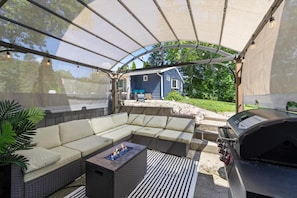 A covered outdoor seating area with a grill and a fire feature. - The Crows Nest Cottage 1 (Franklin)