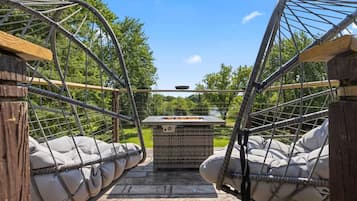 A hammock bridge with two cushioned seating areas and a central fire pit.