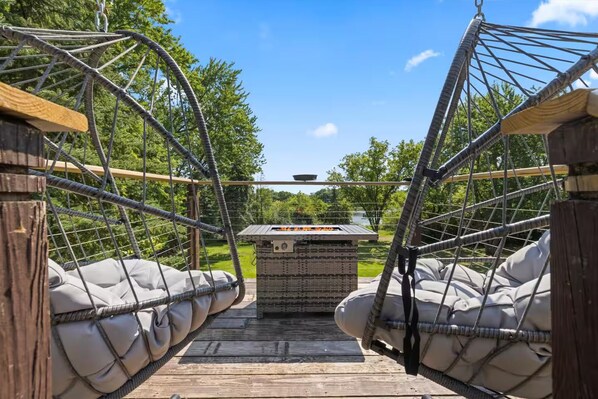 A hammock bridge with two cushioned seating areas and a central fire pit.