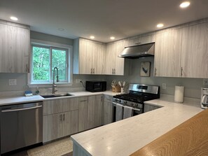 Een moderne keuken met roestvrijstalen apparatuur, houten kastjes en een raam dat voor daglicht zorgt.