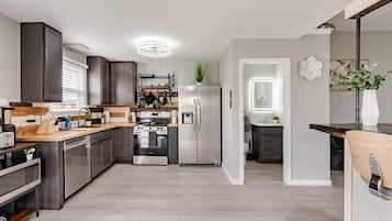 Et moderne køkken med rustfrie hvidevarer, træbordplader og en indbygget ovn.