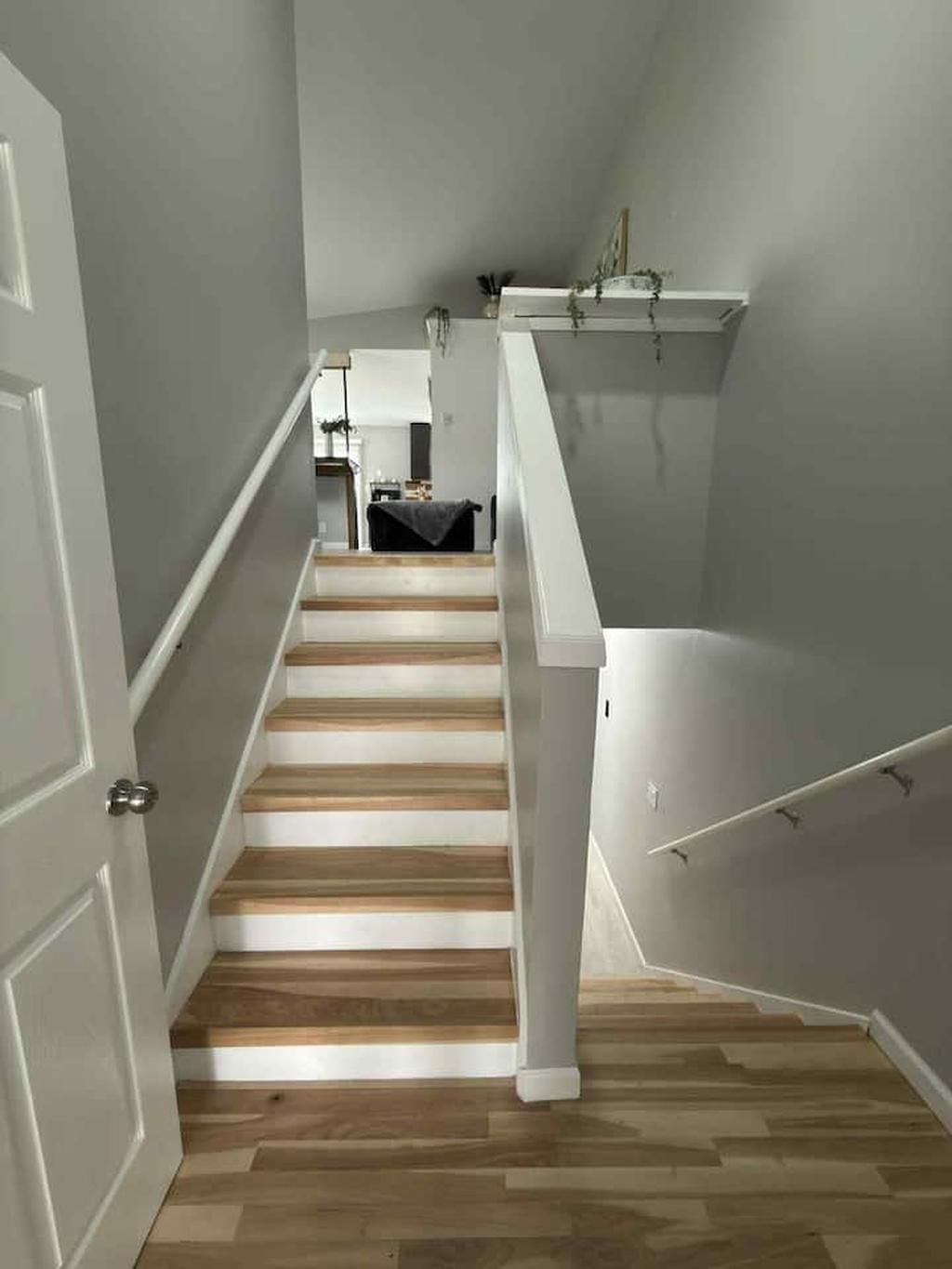 Un escalier avec des marches en bois et des rampes blanches menant à un palier.