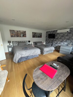 Ein Hotelzimmer mit Bett, Schreibtisch, Stuhl, Fernseher und Bildern an der Wand.