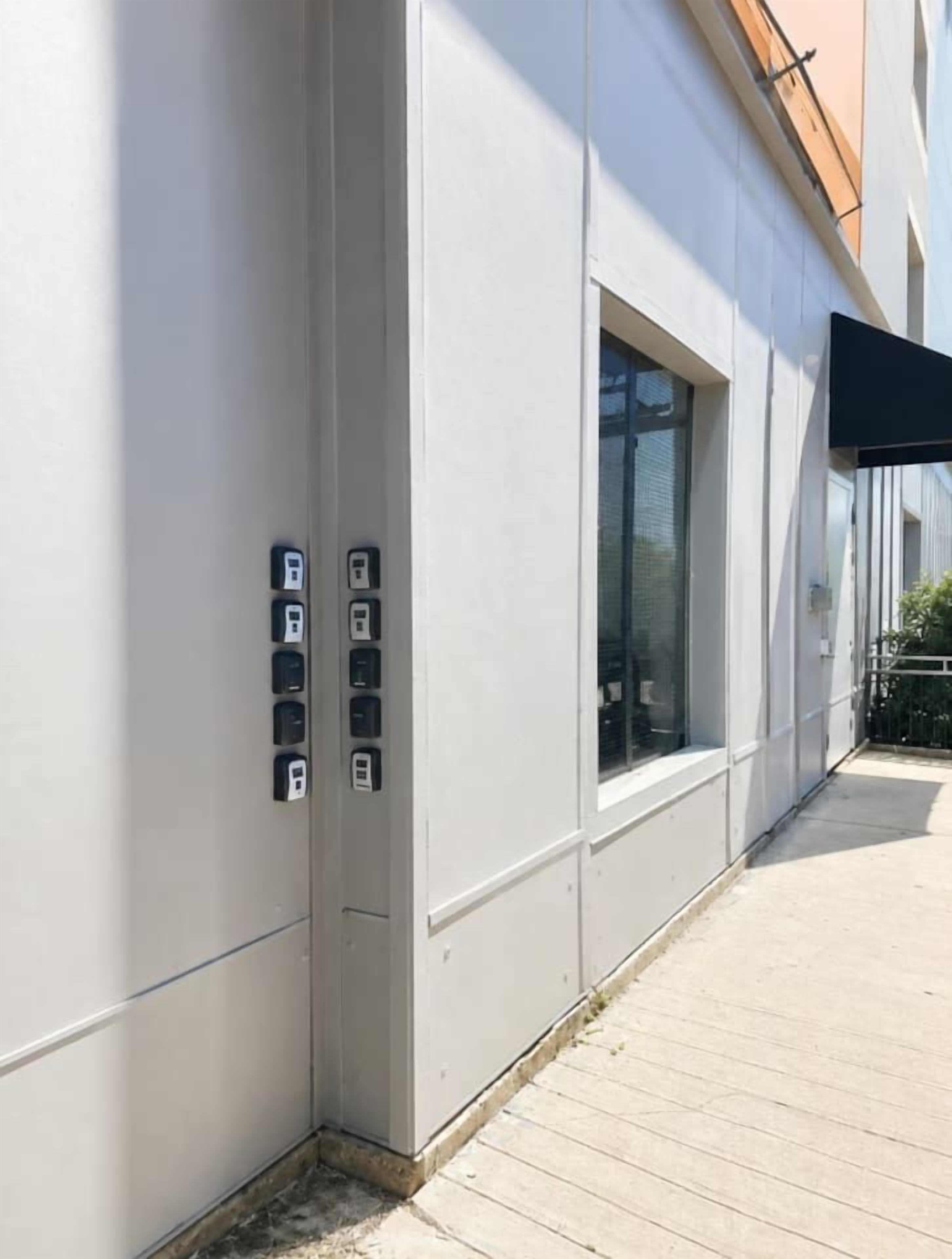 L’extérieur d’un bâtiment présente un design moderne, avec une grande fenêtre et une série de prises électriques fixées au mur.