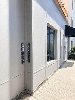 L’extérieur d’un bâtiment présente un design moderne, avec une grande fenêtre et une série de prises électriques fixées au mur.