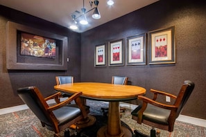 A conference room with a round table, four chairs, and framed artwork on the walls.