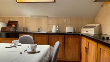 A compact kitchen with a dining area, equipped with a toaster, kettle, and a small refrigerator.