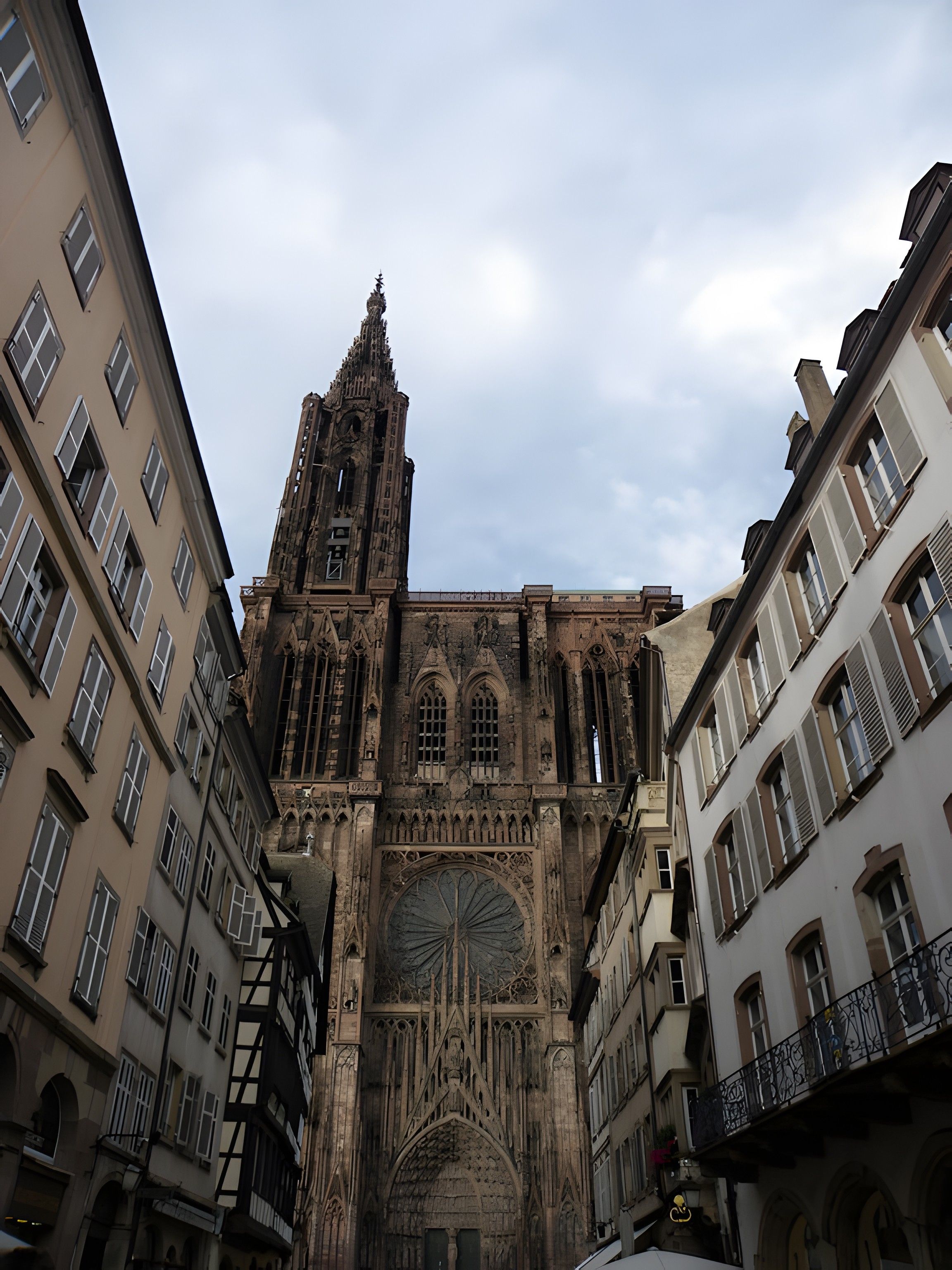Uma catedral histórica com uma alta torre sineira, arquitetura gótica e uma grande rosácea central.