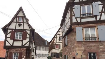 Une rue étroite bordée de maisons traditionnelles à colombages, un lampadaire bien visible et un ciel dégagé.