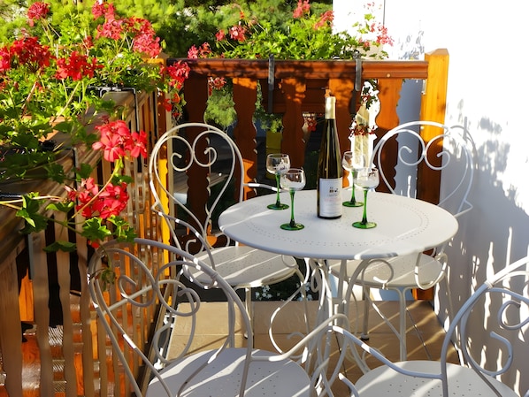 Un patio al aire libre con una mesa redonda, cuatro sillas y una botella de vino.