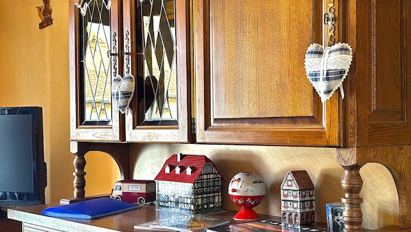 Une pièce dotée de meubles en bois, d’un téléviseur et de divers objets décoratifs, notamment des maquettes de maisons et un globe terrestre.