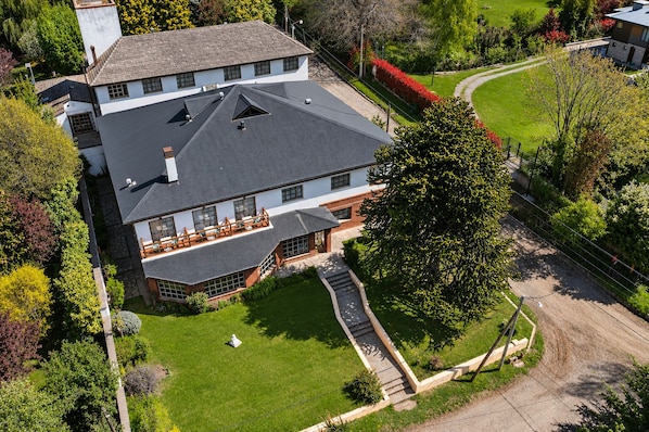 Un'ampia casa a due piani con tetto spiovente, veranda coperta e prato curato.