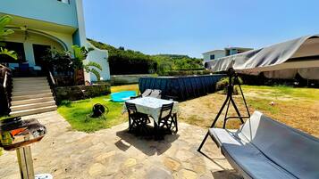 A patio area with a table, chairs, a grill, and a covered seating area.