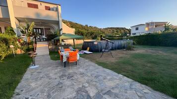 A patio area with a stone pathway leading to a table and chairs, a covered seating area, and a swing set.