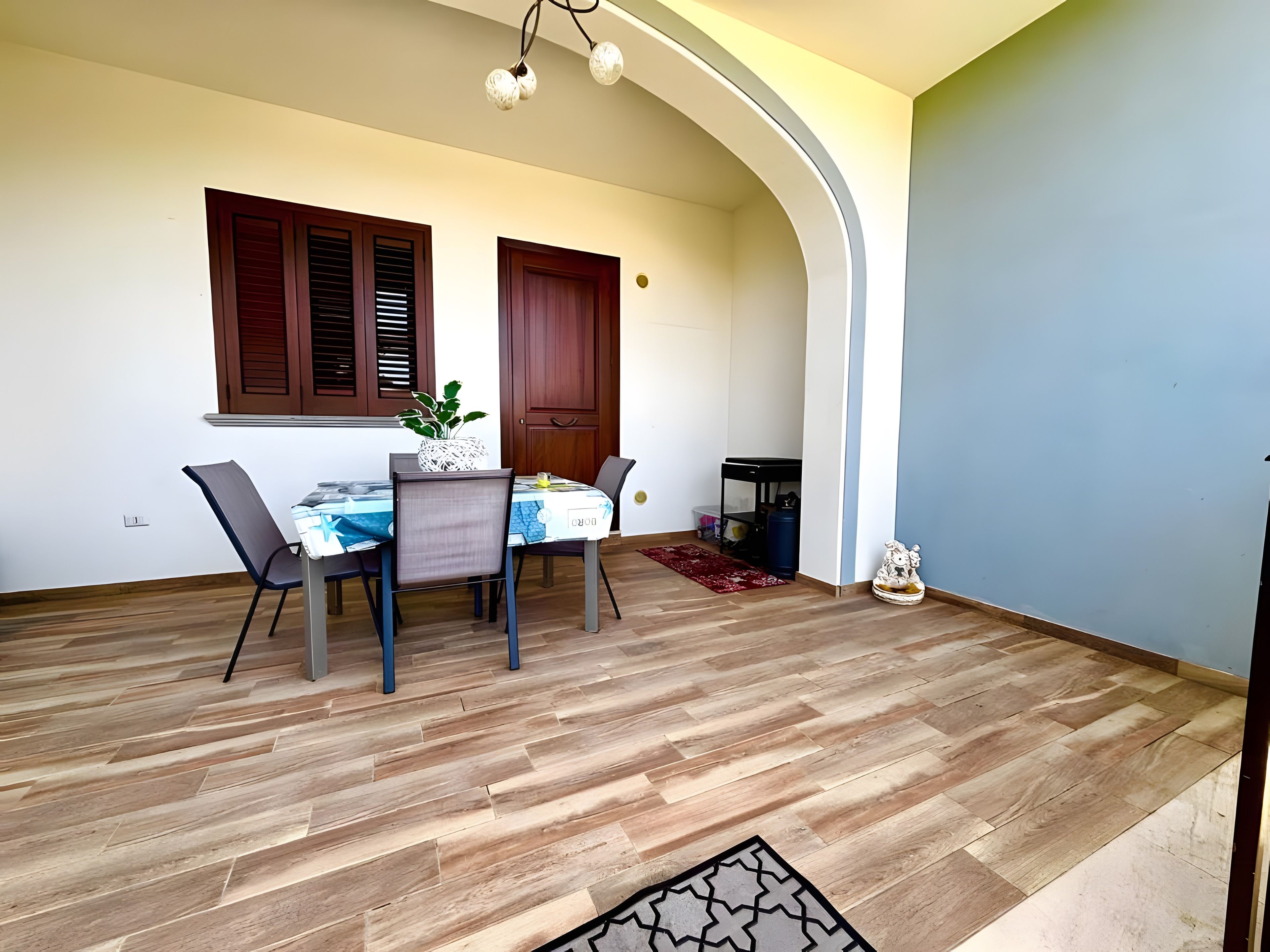 Un comedor con una mesa dispuesta para cuatro personas, suelo de madera y una lámpara en el techo.