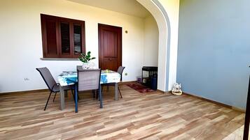 Un comedor con una mesa dispuesta para cuatro personas, suelo de madera y una lámpara en el techo.