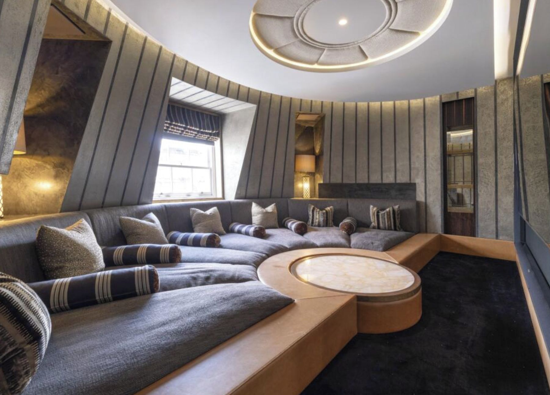 A modern living room with a curved sectional sofa, a round coffee table, and a built-in fireplace.