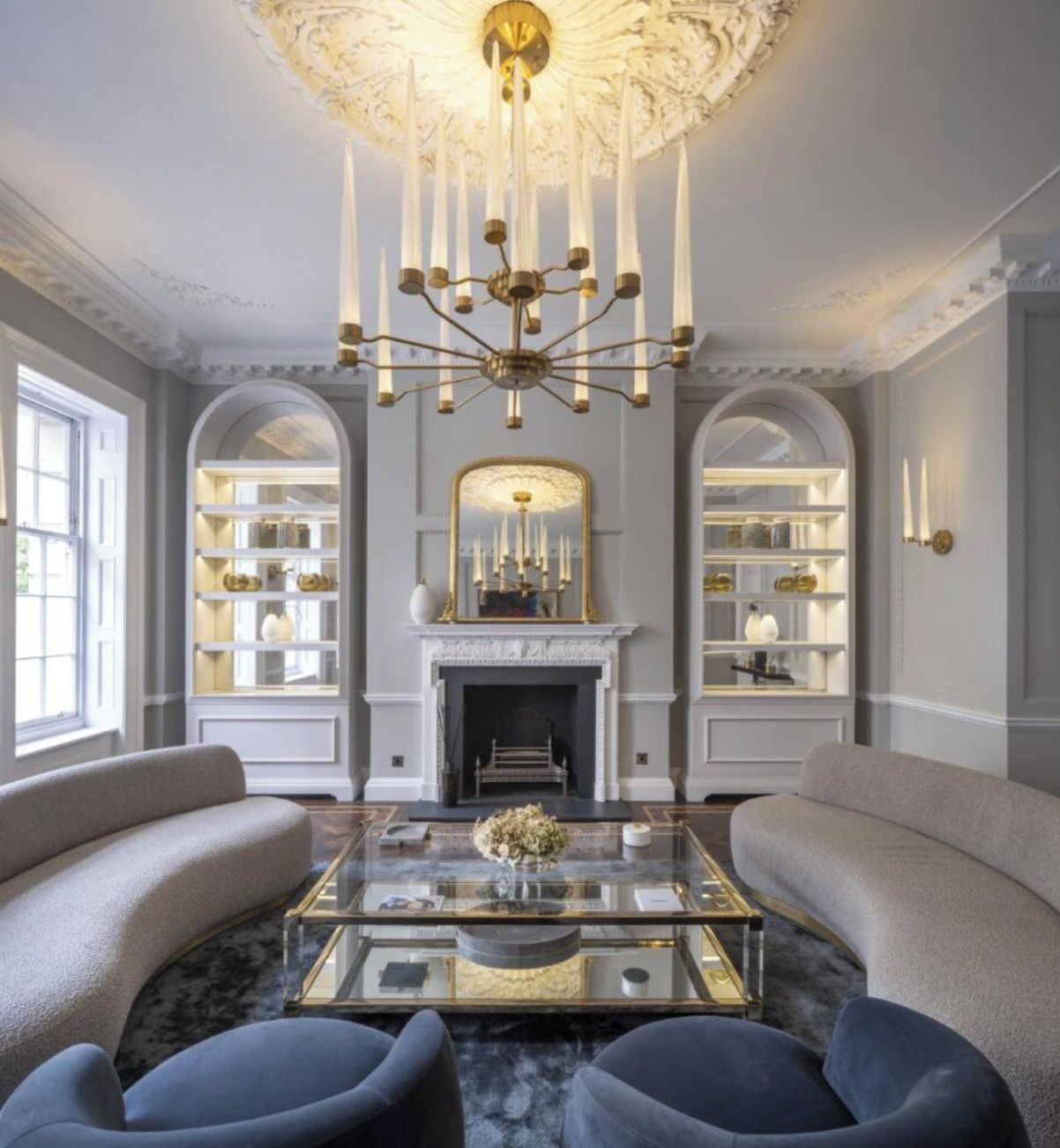 A room with a fireplace, a chandelier, and a glass coffee table.